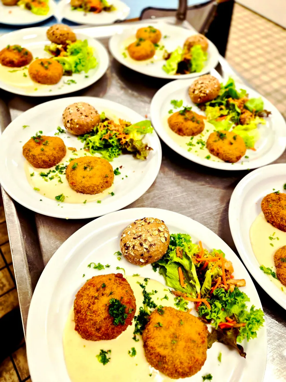 Assiettes de croquettes maison servies avec salade, petits pains et sauce